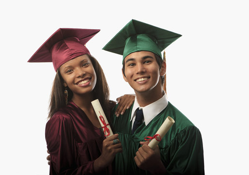 multi racial couple in cap, gown with diploma at graduation