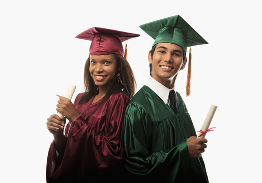 multi racial couple in cap, gown with diploma at graduation