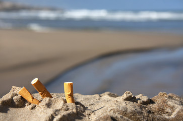 three cigarette butts on beach - 23996099