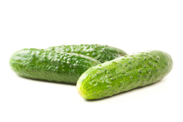 three fresh green cucumbers isolated on white with water drops