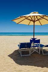 Deck chairs under an umbrella in the sand