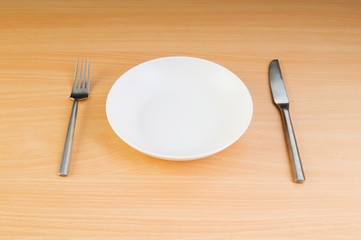 Plate with utensils on wooden table