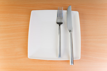 Plate with utensils on wooden table