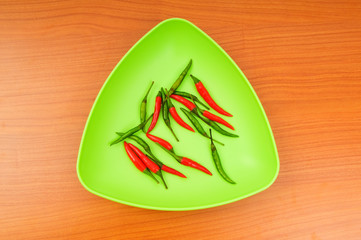 Hot peppers in the plate on wooden table