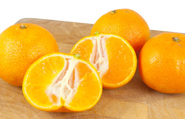 sliced and whole oranges on chopping block on white