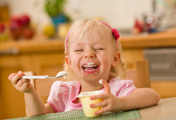 little girl eating yoghurt - obrazy, fototapety, plakaty
