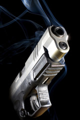 Hot gun on a dark background with smoke rising from the barrel just after a shot