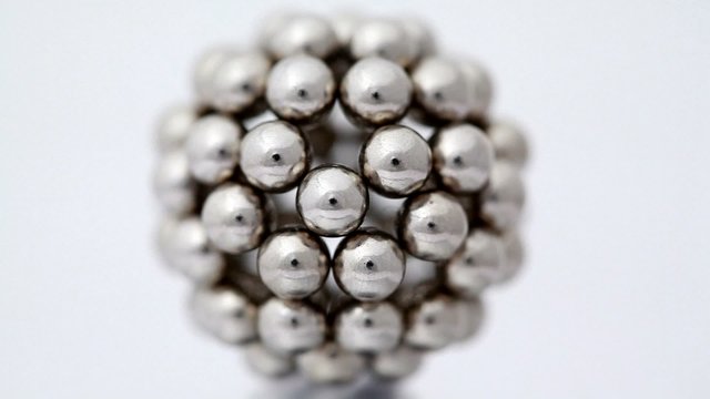 Figure consisting of metallic balls rotate on white