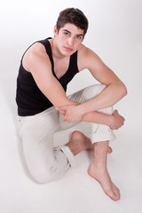 Young man sitting on the floor.  Man looking at the camera.