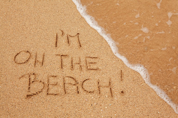 I'm on the beach written in the sand with finger
