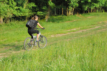 Fototapeta na wymiar woman riding a bike on a road in forest with a bit motion blur
