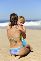 Happy child hugging her mother on the beach