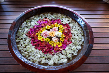 Bowl with water and flowers on wooden floor