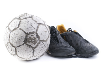 Soccer ball with two old black soccer shoes