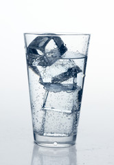 glass with cold mineral water, bubbles and ice