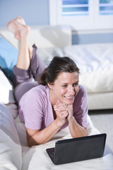 Woman using laptop relaxing on couch