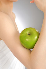 Sporty woman holding green apple with her arm.