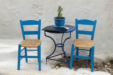 Fototapeta na wymiar Two chairs outside a Greek restauant, in te traditional blue and