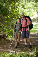Hispanic father and son hiking on trail in woods