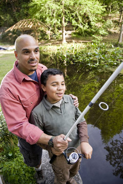 Hispanic Father And Son Fishing In Pond