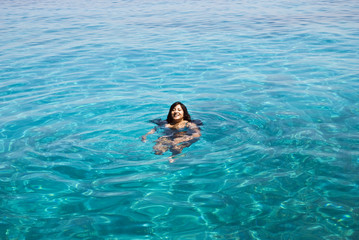 A beautiful indian woman swimming in turquoise blue sea.