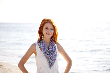 Fototapeta na wymiar Beautiful red-haired girl at sunrise on the beach.