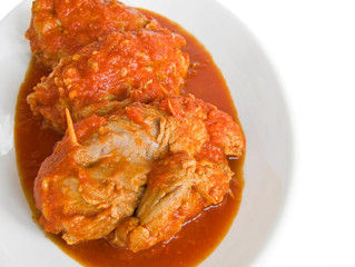 Meat roulade in tomato sauce on white dish.