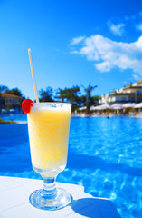 cocktail in glass on a background blue water of pool