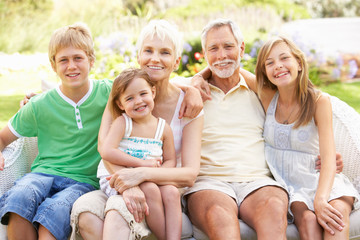 Grandparents And Grandchildren Relaxing In Garden