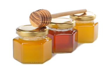 honey in bottles and wooden dipper isolated