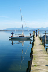 A couple prepare their sailing boat in Chiemsee lake pier