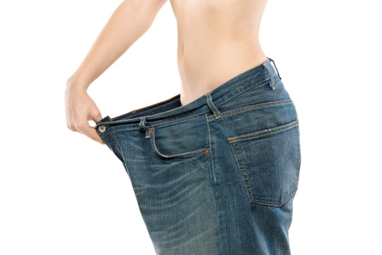 Female showing her lost weight by putting on a jeans