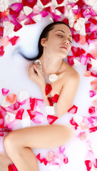 Obraz na płótnie Canvas Attractive naked girl enjoys a bath with milk and rose petals