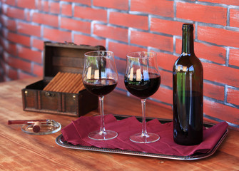 Two glasses of red wine with bottle and open box of cigars