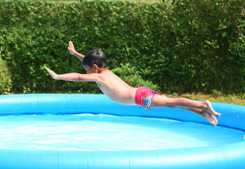 Junge springt ins Wasser eines Pool