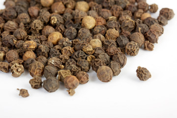 Detail shot of a pile of black peppercorns. All isolated