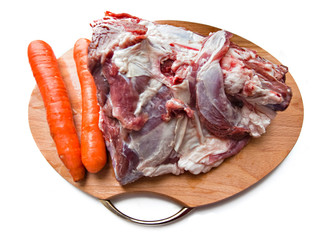 red raw meat and carrots over white on wooden plate