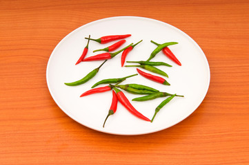 Hot peppers in the plate on wooden table