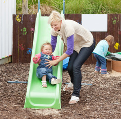 Little girl and her beautiful mother having fun with a chute