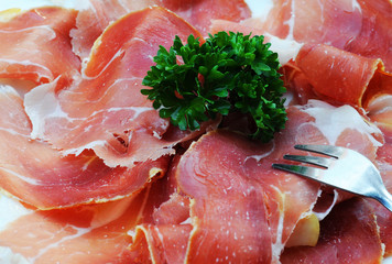 Thin sliced serrano ham with parsley and fork