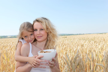 Mother and child with bowl of cereals in wheat field