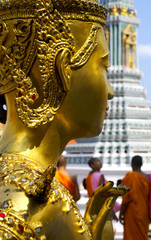 Close-up angle of buddha's head with monks in the background in