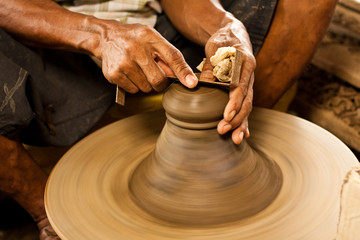 potter's wheel and hands of craftsman hold a jug