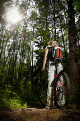 Naklejka premium young woman with bicycle in forest