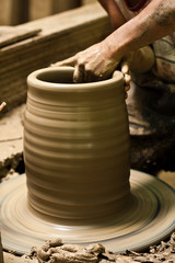 potter's wheel and hands of craftsman hold a jug