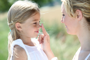 Mother and daughter putting sunscreen on their face