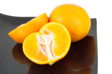 cut segmented orange on black plate on white