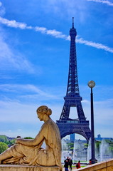 Tour Eiffel et statue de femme en pierre.Ciel bleu.