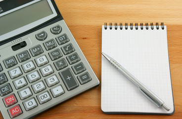 Calculator, pen and notebooks on wooden table