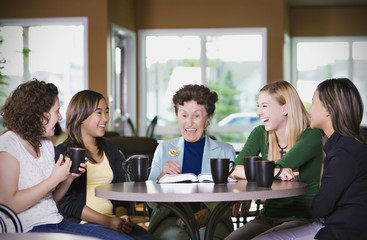 Group Of Girls Listening To Senior Woman In Restaurant